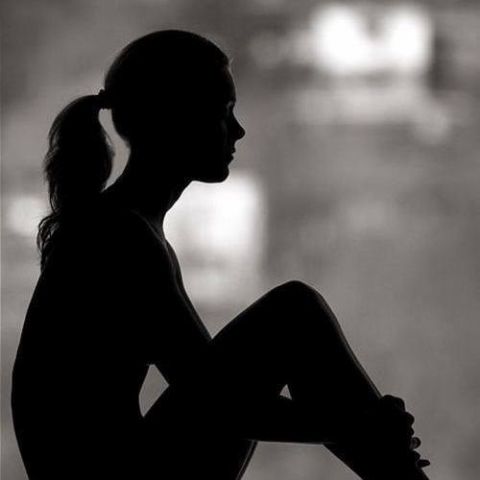 ひざを抱えて座る女性のシルエット
