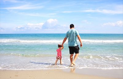 浜辺を歩く父と子の後ろ姿
