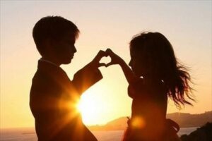 夕日を背に指でハートをつくる二人のシルエット