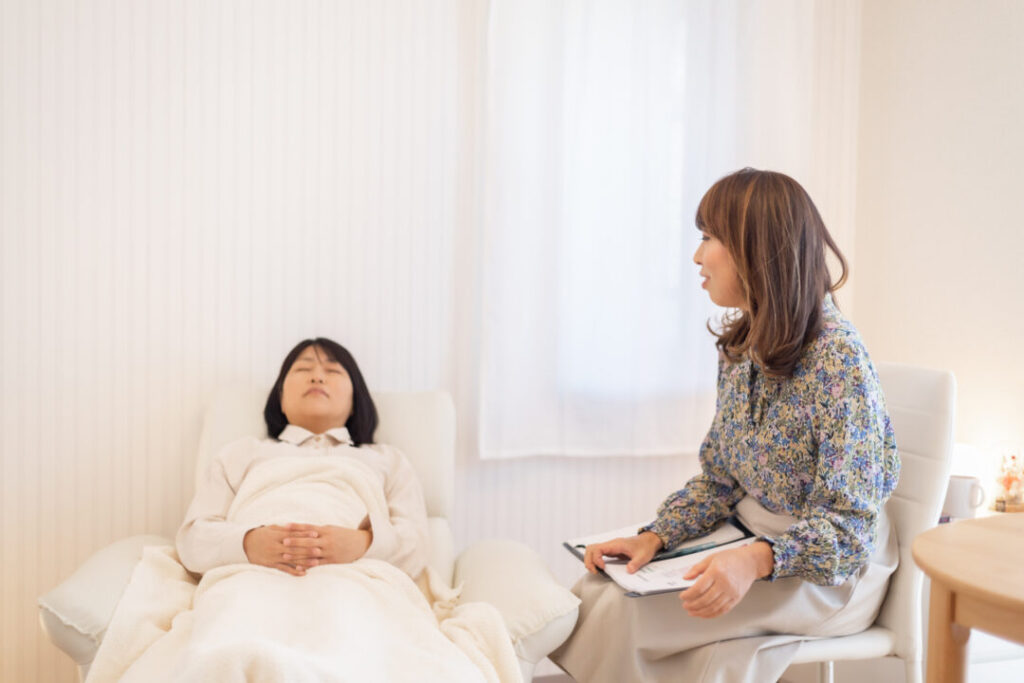ヒプノセラピーの個人セッション|催眠誘導を受けるクライアントと寄り添うセラピスト紫紋かつ恵