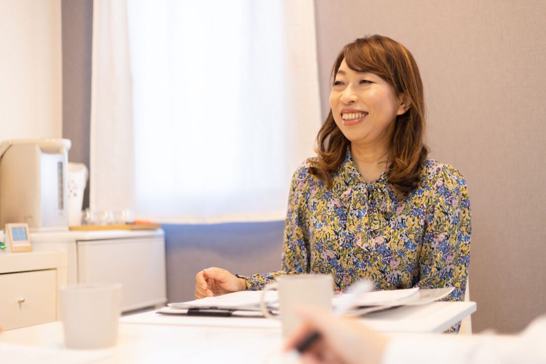 セッションルームで笑顔で話す公認心理師・ヒプノセラピストの紫紋かつ恵